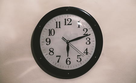 Closeup view of an old retro clock on white wall.の写真素材