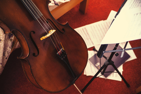 Old cello and music sheets in domestic room, besides bed. Conceptual composition of learning cello. の写真素材