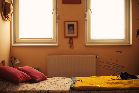 Interior of a teenage girl, closeup view on bed besides windows and various personal things and lifestyle objects. の写真素材