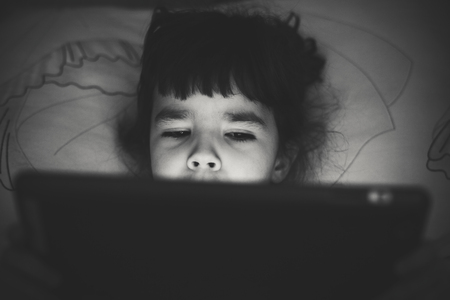 Portrait of a small child, watching a notebook before sleeping. の写真素材