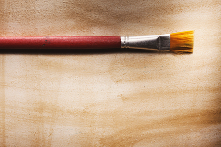 One red wooden paintbrush on wooden surface.の写真素材