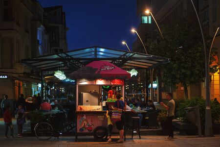 Cacak, Serbia - July 18, 2018: Summer season in Cacak town, central sidewalk, cafes and restaurants during night.のeditorial素材