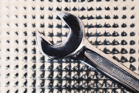 Abstract composition of metal wrench and surface.