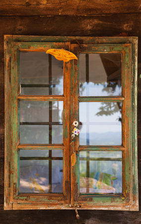 Closeup view of an old vintage style wooden window, exterior details of an old wooden cottage and big interesting butterfly.の写真素材