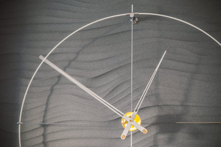Modern metal clock on interesting wall background.