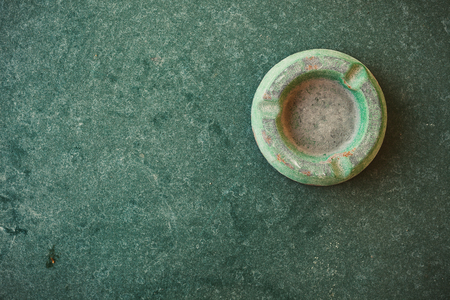Abstract composition of an old and dusty green ashtray on green table.の写真素材