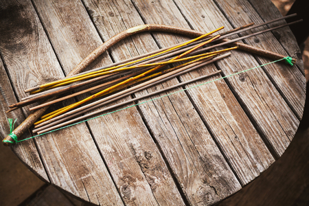 Old fashioned handcrafted arc and arrows for play on old wooden table.の写真素材
