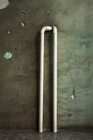 Two radiator pipes and old ruined green wall. Part of an old building.の写真素材
