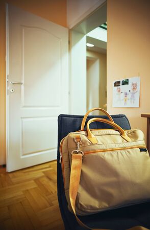 Prepared bag for laptop on home chair, home interior in blurryの写真素材