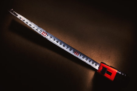 Metering tool in centimeters, on brown  surface, in dark.