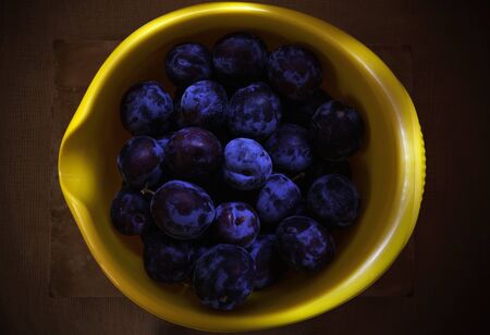 Closeup view of fresh plums in yellow dish.の写真素材