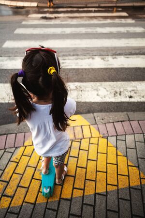 Small girl on scooter in front of a pedestrian cross.の写真素材