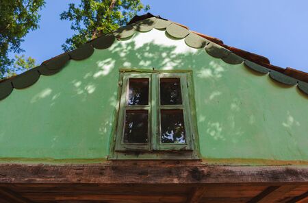 Exterior of an old wooden house, details of small loft window and green roof.の写真素材