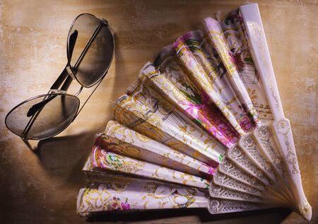 Decorative fans and sunglasses on wooden board.の写真素材