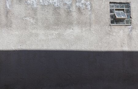 Texture of a wall with one window and shadow.の写真素材