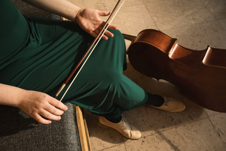 Teenage girl with her cello, posing in a hall.