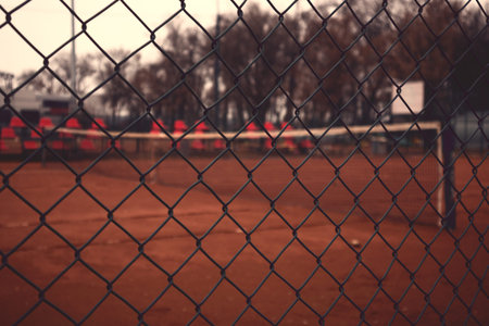 View on empty tennis yard through fence.
