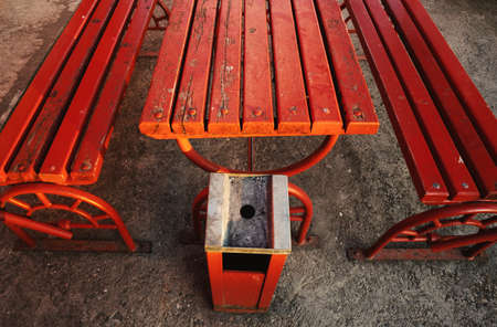 Details of an old red wooden table, two benches and metal ashtray.の写真素材