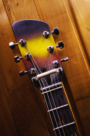 Closeup view of a neck and colorful head of an old guitar.