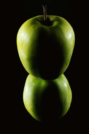 One green apple on mirror in dark.の写真素材