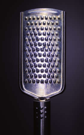 Closeup view of one metal grater on purple background, minimalistic approach, studio composition.の写真素材