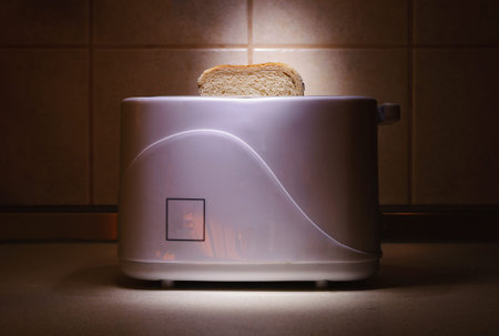 Closeup of piece of bread in toaster on kitchen desk.