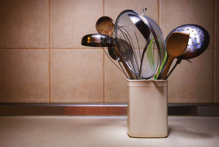 Various kitchen utensils in ceramic container on kitchen desk.の写真素材