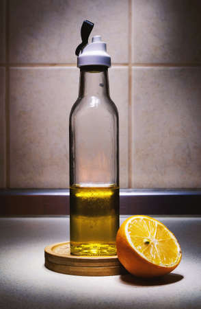 One small bottle of oil half full and half of lemon on kitchen desk.の写真素材