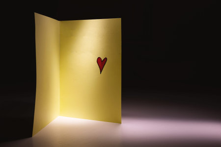 Open gift card with painted red heart on white table.