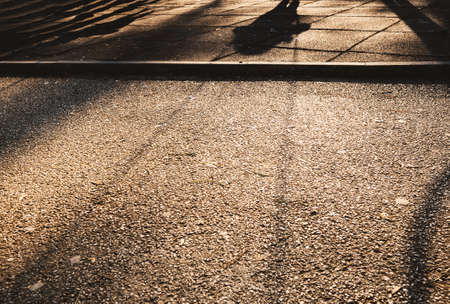 Shadow on the asphalt of a small child on a swing in the park.の写真素材