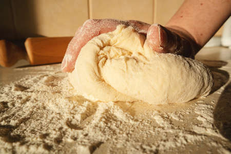 Preparing the dough for bread, kneading the dough with a rolling pin on the table.の写真素材