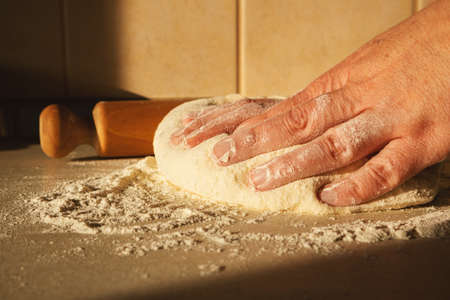 Preparing the dough for bread, kneading the dough with a rolling pin on the table.の写真素材