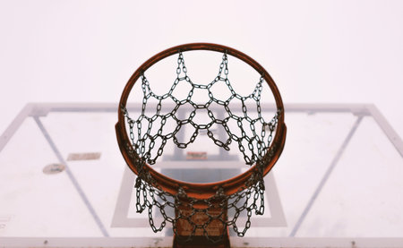 Bottom view of basketball hoop, gloomy day, metal mesh, simple composition with focus on chains.