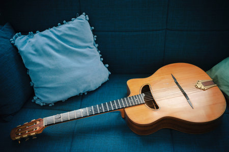 One old gypsy acoustic guitar on a blue sofa with pillows.の写真素材
