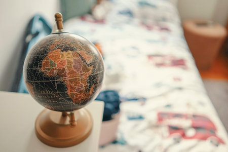 Closeup view on small globe standing on table in kid's room, bed in blurry background.の写真素材