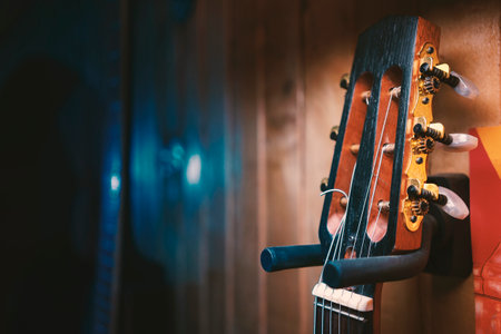 Detail from a guitarist's room, an old acoustic guitar hanging on a wooden wall. Close up view.の写真素材