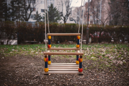 One colorful wooden swing, for the youngest, in the background of the city building.の写真素材