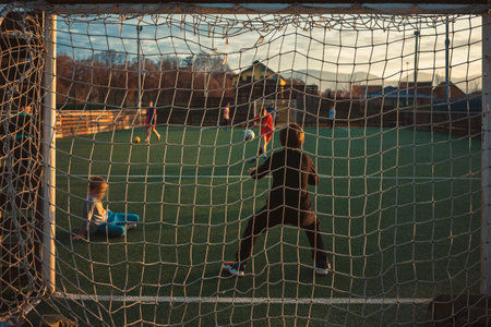 Football training for children, the goalkeeper got ready to defend him from the ball that was just sent. in the background the field and children.の写真素材