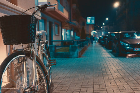 Street night scene, parked bicycle leaning against the wall, details of the sidewalk and street in the background.の写真素材