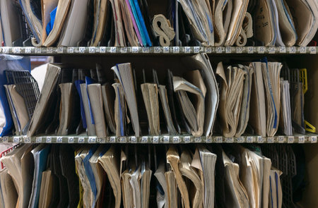 Various notebooks, papers and forms on a shelf under serial numbers, detail from the post office.の写真素材