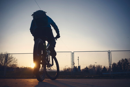 A boy rides a bike, practices on the asphalt at dusk.の写真素材