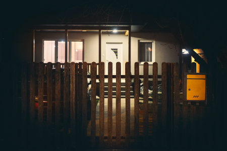A closed wooden fence in front of a modern new house at night.の写真素材