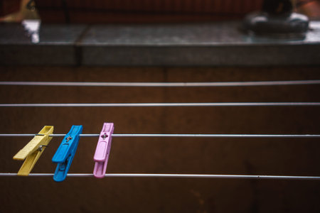 Three yellow, blue and pink clothespins on a clothesline.