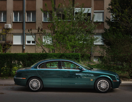 Modern and luxurious car, green metallic color with strong reflection, parked in front of the building.の写真素材