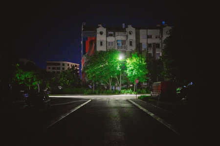 Night street scene in Balkan town, parked cars, no people, details of street lighting.