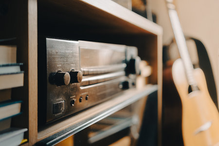 An amplifier and receiver as a home hi-fi system, an old model on a shelf in the room, an acoustic guitar can be seen in the background.の写真素材