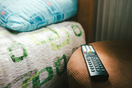 Remote control on the stool next to the bed in the room.の写真素材