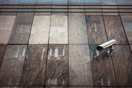 Video surveillance, a camera on the marble wall of the building.