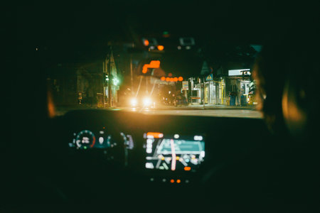 View from the back seat of a car at an intersection at night.
