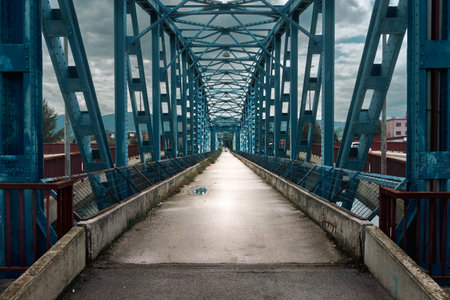 An old pedestrian bridge with an interesting arched metal structure, during the day in spring.の写真素材